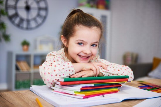 A little girl smiling with books at hand
