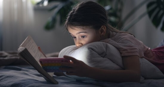 A little girl using phone while studying