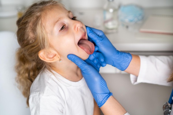 Girl showing her tongue and throat to speech therapist for inspection