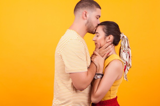 A guy kissing on the forehead of his partner