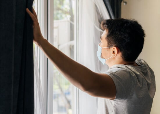 A man at home wearing a mask